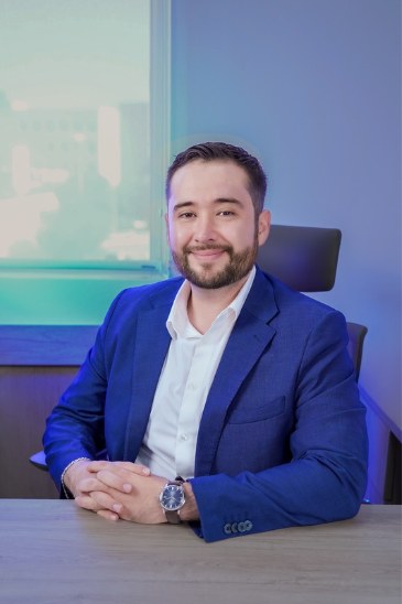 Retrato del Dr. Erick Alvidrez sentado en su escritorio